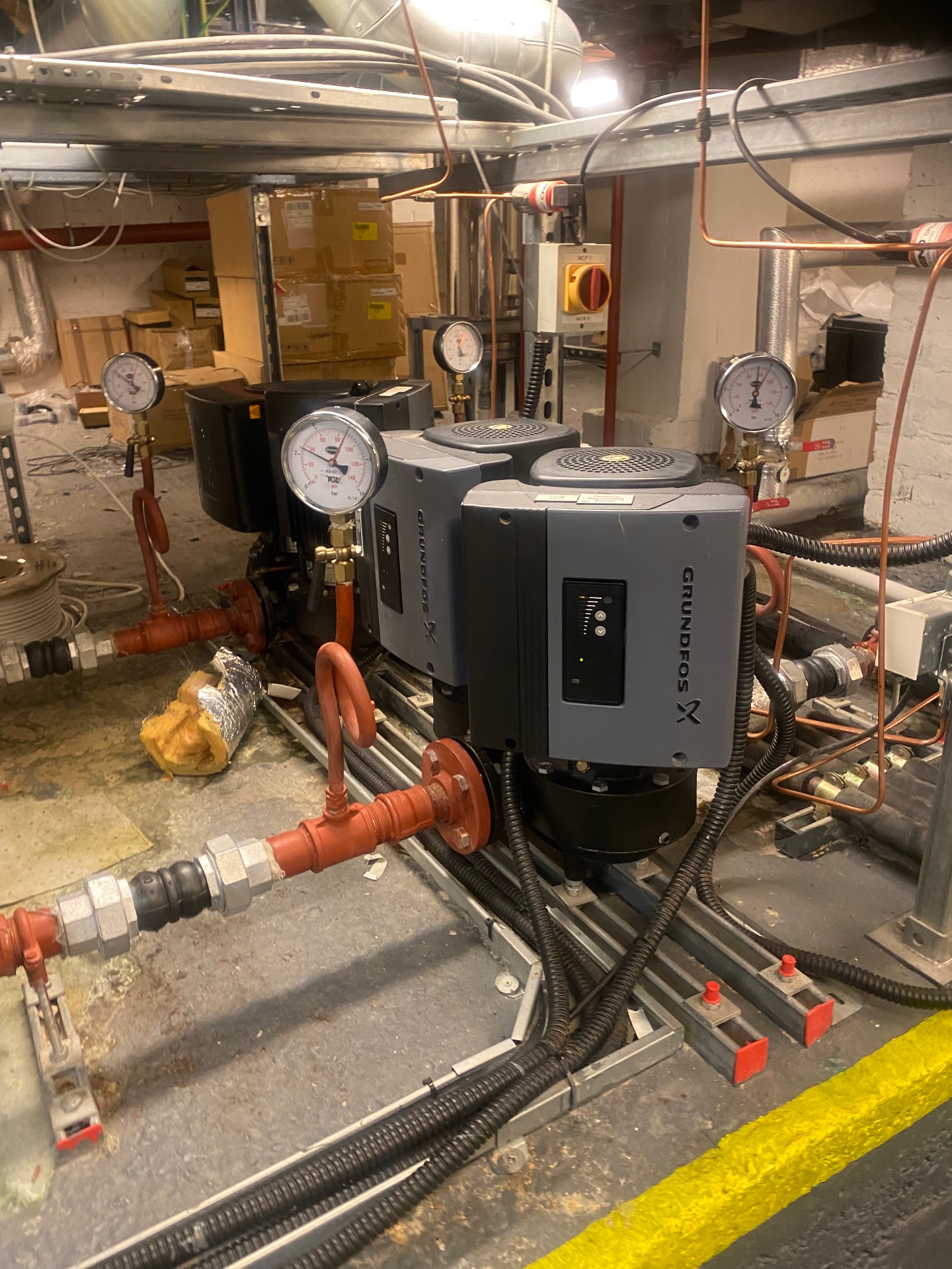 Grundfos circulation pumps with pressure gauges requiring regular maintenance in commercial heating system